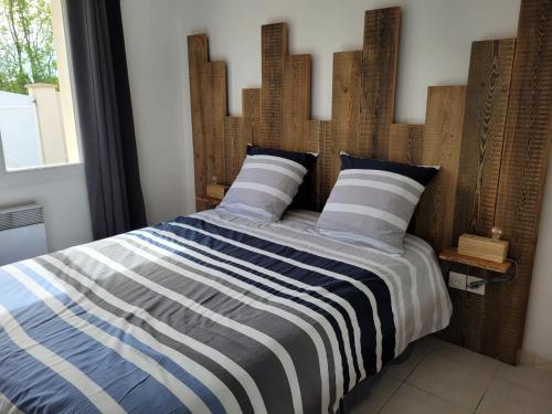 une chambre avec un grand lit avec une tête de lit en bois dans l'établissement Maison sur ile d'Oléron, à Saint-Pierre-dʼOléron