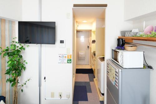a small kitchen with a tv on the wall at Kameari 1003 Budget Stay High Floor Near Station Mall Disney Access in Tokyo