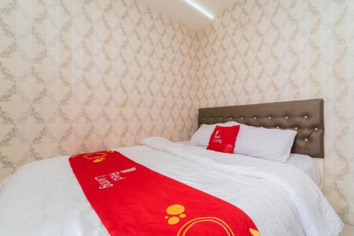 a bed with a red blanket on top of it at RedLiving Apartemen Bassura City - Premium Property in Jakarta