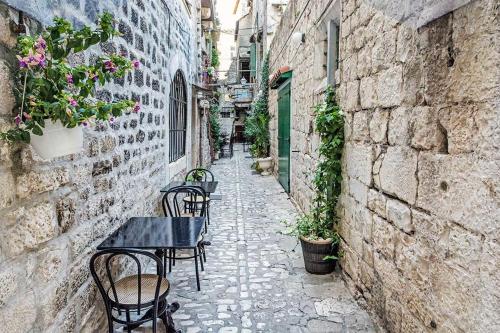an alley with tables and chairs in an alley at Guesthouse Ana Trogir Old Town in Trogir