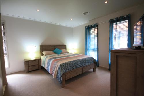 a bedroom with a bed with two night stands and two windows at Yass Valley Stays - Easy self check-in in Yass