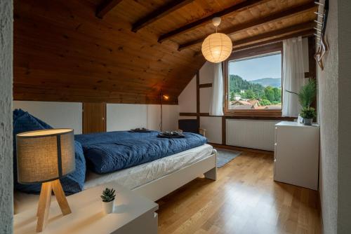 a bedroom with a blue bed and a large window at Jungfrau-View Apartment, terrace & free parking in Wilderswil