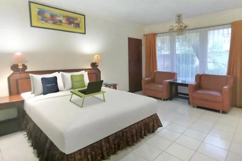 a bedroom with a large bed and two chairs at Urbanview Hotel Bahtera Tarakan by RedDoorz in Sibengkok