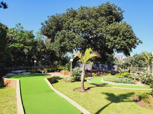 a park with green grass and a palm tree at Santana 804 Beachfront Apartment with spectacular sea views in Margate