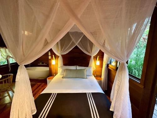 a bedroom with a canopy bed and a bath tub at Koompartoo Retreat Bellingen in Bellingen