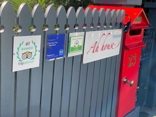 a fence with signs on it with a red mailbox at Ah House City B&B Nelson in Nelson