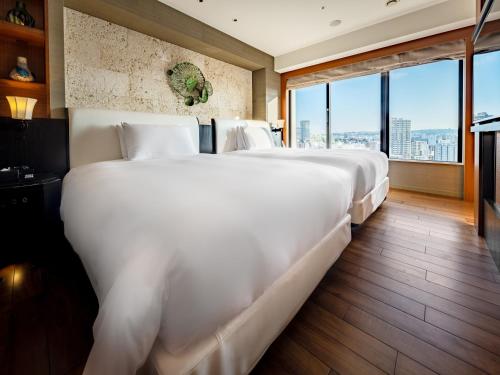 two beds in a hotel room with a large window at Hyatt Regency Naha, Okinawa in Naha