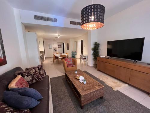 ein Wohnzimmer mit einem Sofa und einem Flachbild-TV in der Unterkunft Apartment at Samarah Dead Sea Resort in Sowayma