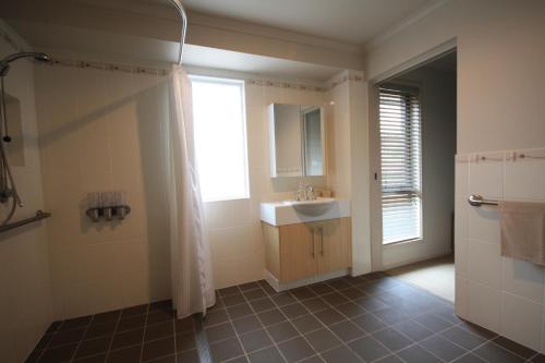 ein Bad mit einem Waschbecken und einer Dusche mit einem Fenster in der Unterkunft Yass Valley Stays - Easy self check-in in Yass