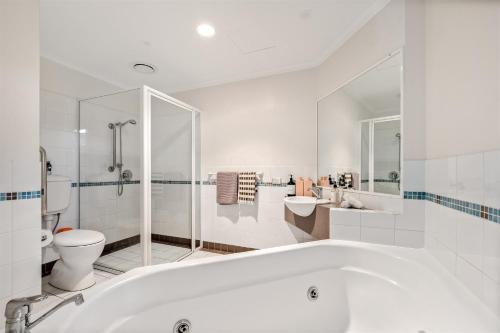 a white bathroom with a tub and a toilet at 107 Apartments Margaret River in Margaret River Town