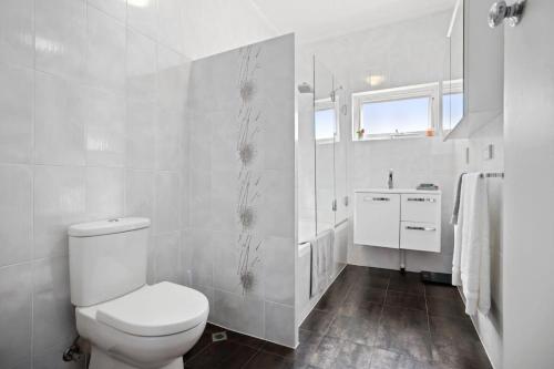a white bathroom with a toilet and a sink at Sunset Sanctuary Glenelg Sth in Glenelg