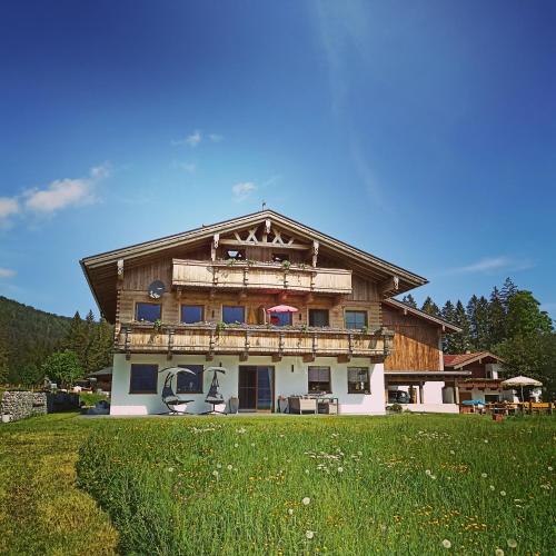 a large wooden house with a green field in front of it at Ferienwohnung Hinterwinkl in Achenkirch