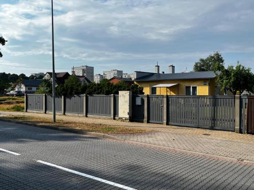 uma cerca ao lado de uma rua com uma casa em Cozy family house em Ventspils