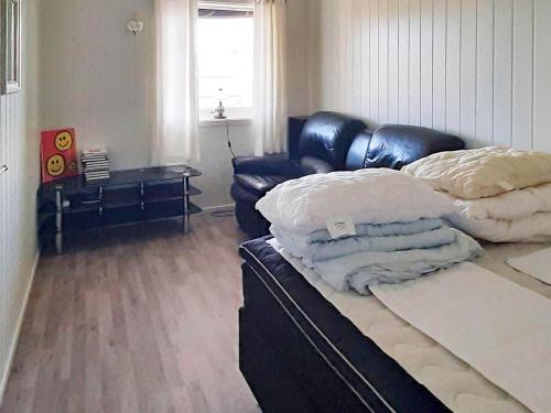 ein Wohnzimmer mit einem Ledersofa und einem Bett in der Unterkunft Holiday home SORTLAND II in Sortland