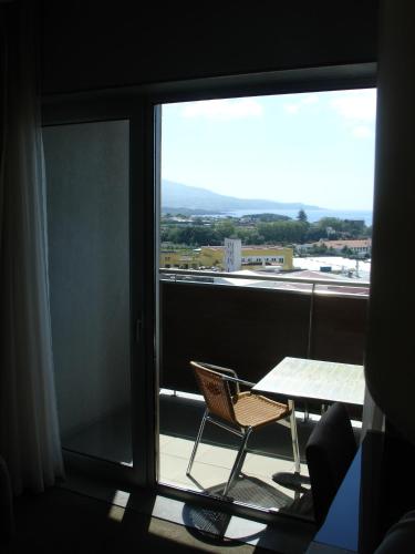 a table and chair on a balcony with a view at VIP Executive Azores Hotel in Ponta Delgada