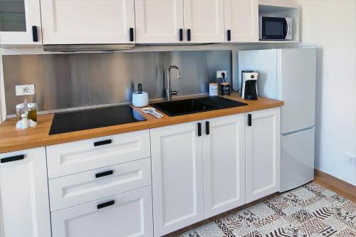 a kitchen with white cabinets and a sink at Villa Paradiso in Scopello