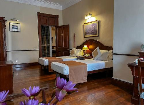 a hotel room with two beds and purple flowers at Queen's Hotel in Kandy