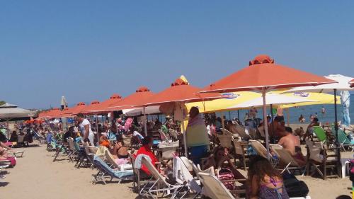a crowd of people sitting on the beach under umbrellas at VILLA AVATOS 3 - Near to the port of Rafina and the airport of Athens in Áyios Spirídhon