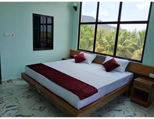 a bedroom with a large bed with two windows at Hotel Gridhakuta International in Rājgīr