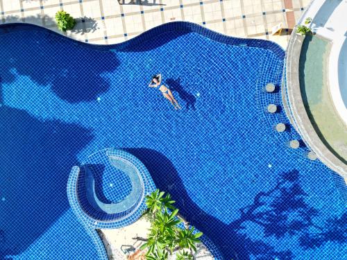 an overhead view of a man swimming in a swimming pool at Phuket Leelavadee Hua Ting Resort in Patong Beach