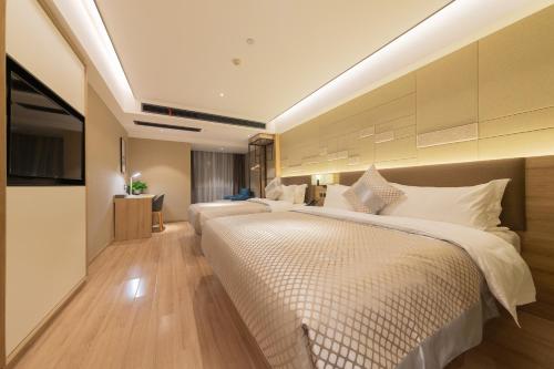 a hotel room with two beds and a television at Morning Hotel, Wuxi Jiangnan University Sunac Cultural Tourism City in Wuxi