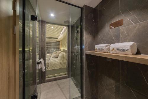 a bathroom with a glass shower with towels on a counter at Morning Hotel, Wuxi Jiangnan University Sunac Cultural Tourism City in Wuxi