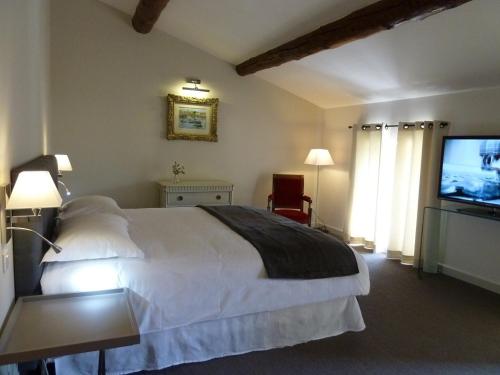 a bedroom with a bed and a flat screen tv at La Maison Saint Jean in Boulbon