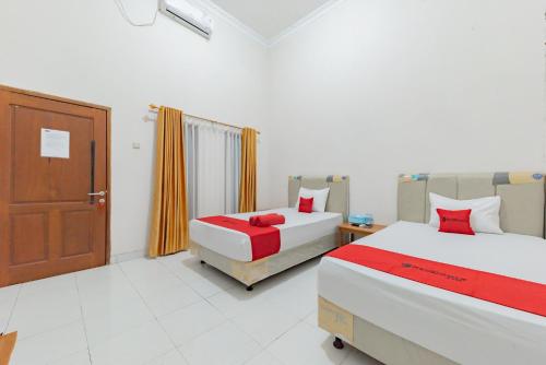 una habitación de hotel con 2 camas y una puerta en RedDoorz near GOR Parenggean 