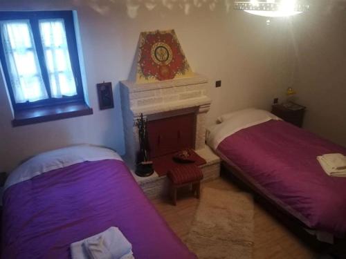 a bedroom with two beds and a fireplace with a clock on the wall at Yono's Traditional House in Ano Ravenia