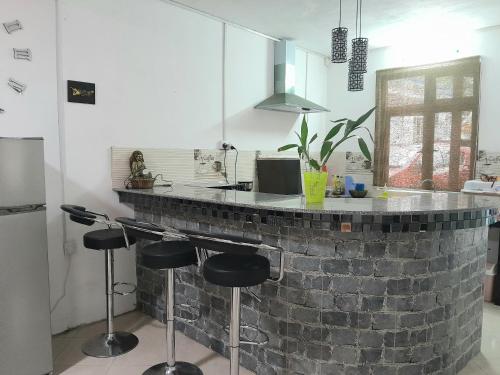 a kitchen with a brick counter with stools around it at Beautiful Affordable House - 5 minutes from the airport and 12 minutes to Blue bay beach in Mon Trésor