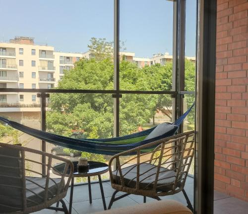 a hammock on a balcony with a view of a building at Green Estate Old Town Apartment, private parking, balcony in Gdańsk