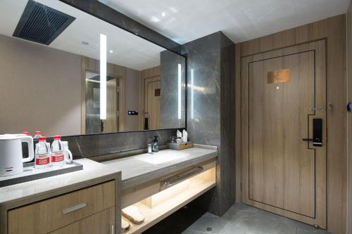 a bathroom with a sink and a large mirror at Morning Hotel, Changsha Yanghu New City Metro Station in Changsha