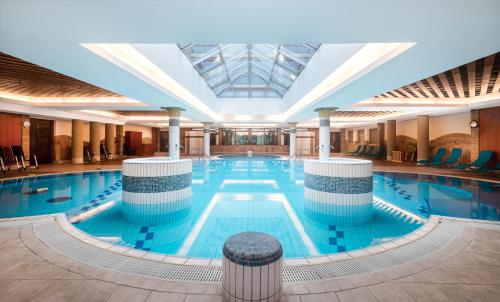 a large swimming pool in a large building at Aquarell Hotel in Cegléd