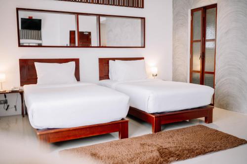 two beds in a room with white sheets and a rug at S 2 Modern Boutique Hotel in Vientiane