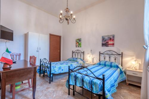 een slaapkamer met 2 bedden, een tafel en een bureau bij Solebarocco del sud - trilocale in Vernole