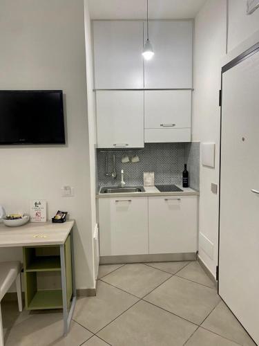 a kitchen with white cabinets and a sink and a table at THE PALACE B&B and Apartments in Santo Stefano di Camastra