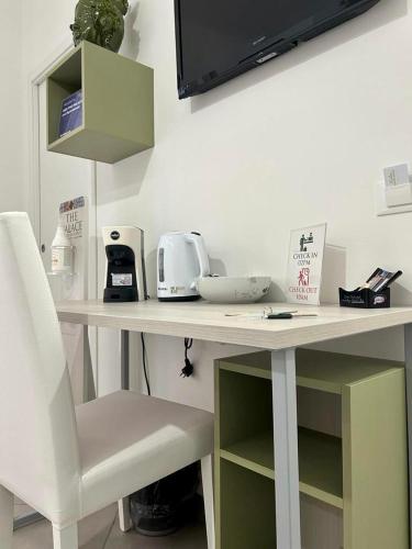 a white table with a chair and a tv on a wall at THE PALACE B&B and Apartments in Santo Stefano di Camastra