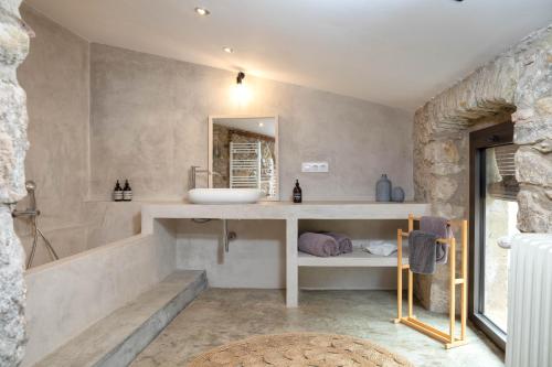 een badkamer met een wastafel, een bad en een spiegel bij Flateli Corçà Townhouse in Corçà