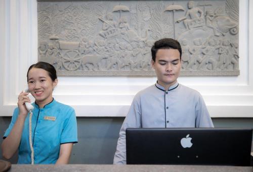 een man en een vrouw die voor een laptop staan bij Siem Reap Comforts Hostel in Siem Reap
