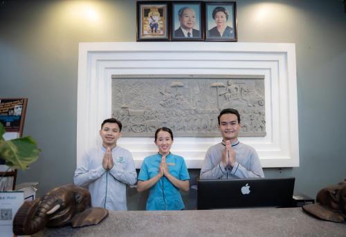 un grupo de tres personas rezando delante de un portátil en Siem Reap Comforts Hostel, en Siem Reap