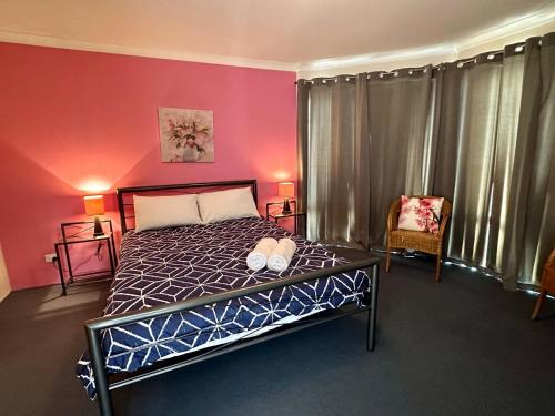 1 dormitorio con cama y pared de color rosa en Sunset on Swift, en Broadwater