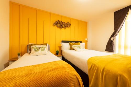 two beds in a room with yellow walls at Sidemersey Livings- Convenient and Central 2-Bedroom Haven in L1, Secured Parking in Liverpool