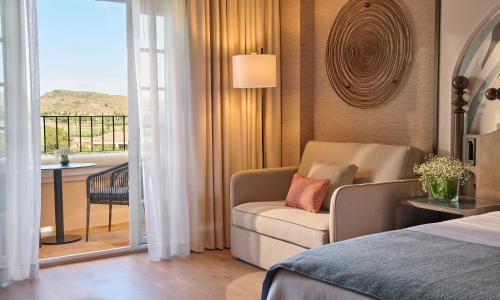 a bedroom with a bed and a chair and a balcony at Grand Hyatt La Manga Club Golf & Spa in La Manga del Mar Menor