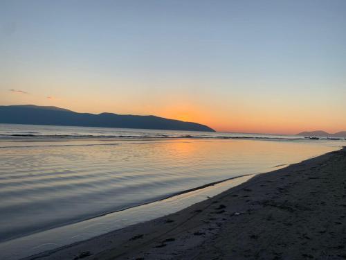 a beach with the sun setting over the water at Arlind's Apartaments in Vlorë