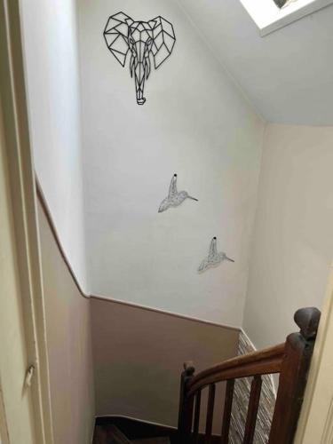 un escalier avec trois animaux au pochoir sur le mur dans l'établissement Downtown cozy cottage - 4 pl -, à Château-Gontier