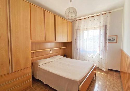 a bedroom with a bed and wooden cabinets and a window at Residence Antonella in Capoliveri