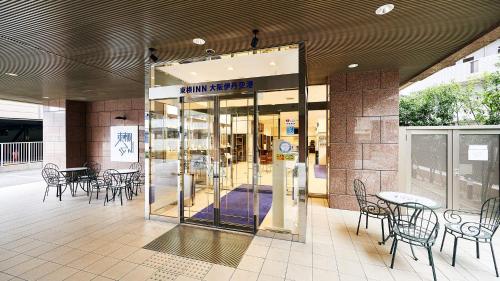 um centro comercial com mesas e cadeiras e uma porta de vidro em Toyoko Inn Osaka Itami Airport em Toyonaka