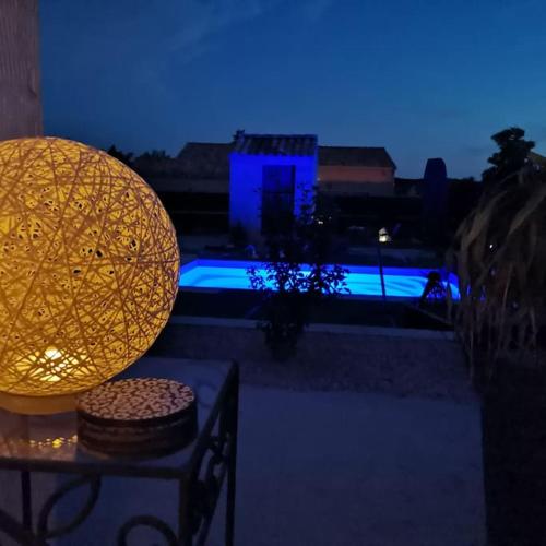 une lampe assise sur une table à côté d'une piscine dans l'établissement Les lauriers, à Uchaux