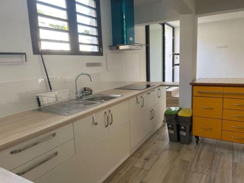 eine Küche mit weißen Schränken und einem Waschbecken in der Unterkunft Chez Romuas in Le Tampon