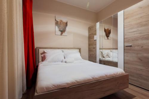 1 dormitorio con cama blanca y cortina roja en City Nest Maria Short Stay en Baia Mare